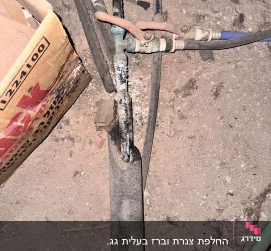 צינור עם ברז מתכת וחיבורים שונים על רצפה מאובקת